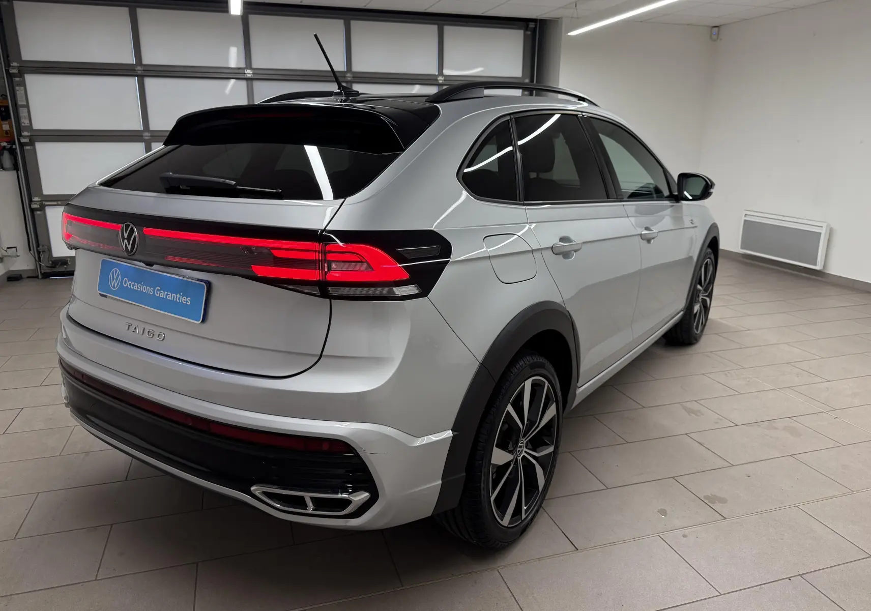 Vue 3/4 arrière droite du Volkswagen Taigo 2025 argent métallisé avec toit noir et jantes alliage 18 pouces.