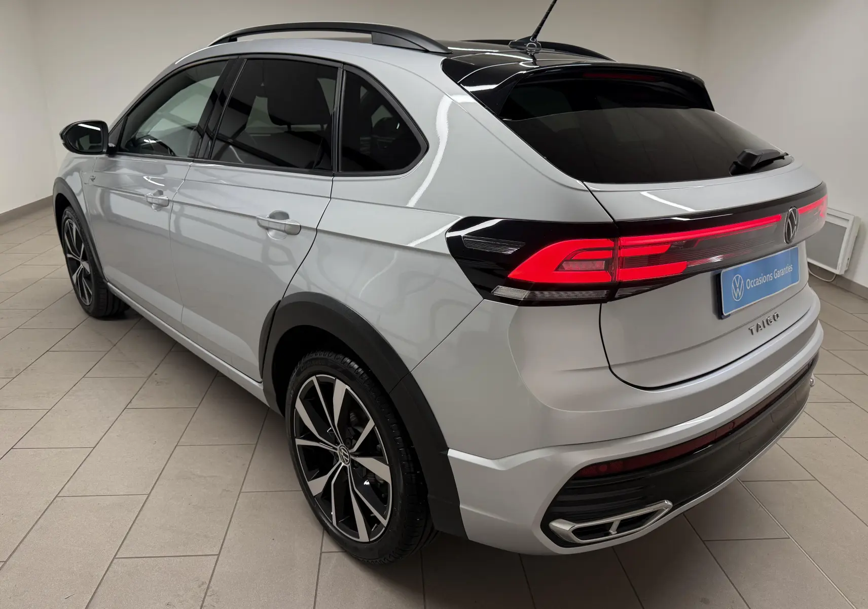 Vue 3/4 arrière droite d'un Volkswagen Taigo 1.5 TSI R-Line 2025 argent métallisé avec toit noir et jantes 18 pouces.
