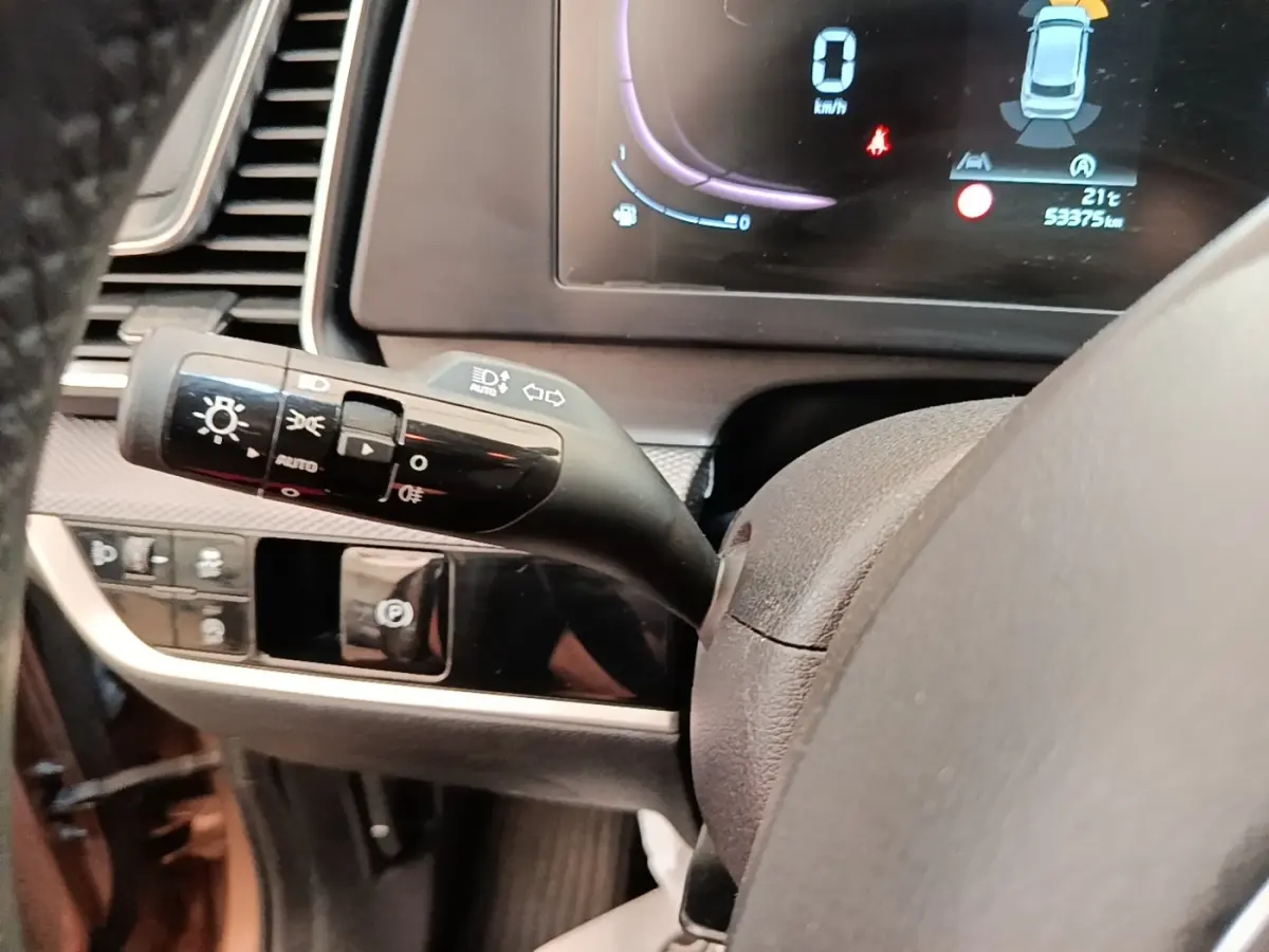 Gros plan sur la manette de commande des phares et clignotants du tableau de bord du KIA Sportage beige 2022.