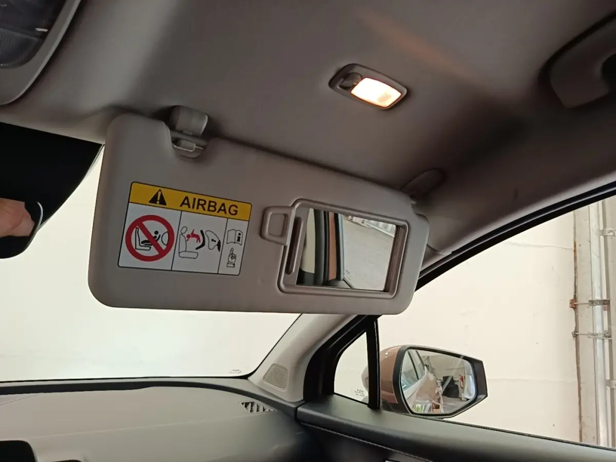 Vue intérieure côté conducteur du Kia Sportage beige 2022, avec pare-soleil rabattable et miroir de courtoisie éclairé.