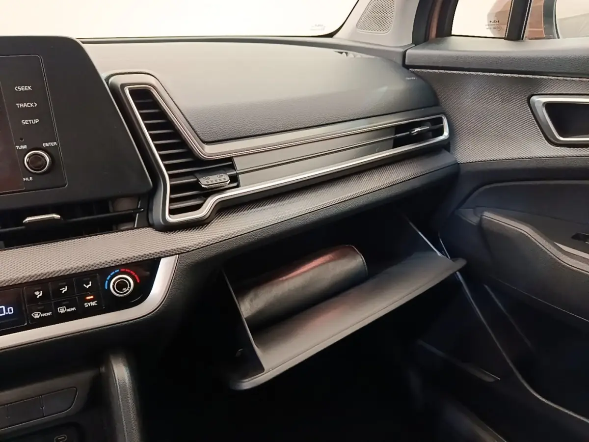 Intérieur du Kia Sportage 2022, vue côté passager sur tableau de bord et boîte à gants ouverte noire.