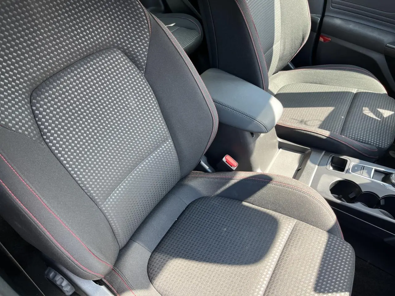Gros plan sur les sièges avant en tissu noir avec surpiqûres rouges de la Ford Focus SW 2025, intérieur lumineux.
