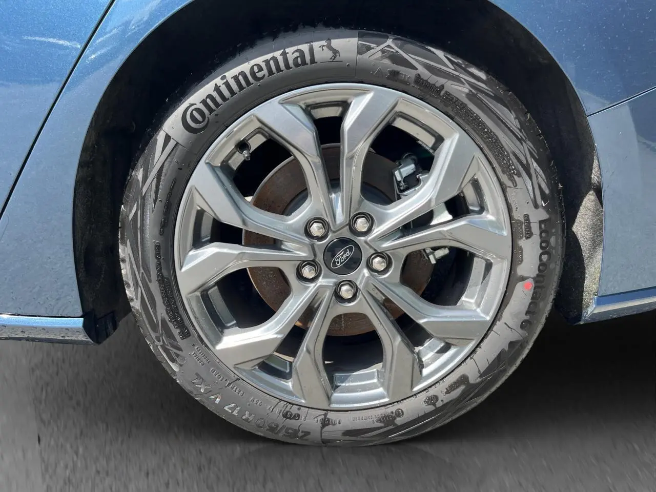 Gros plan sur la roue avant droite d’une Ford Focus SW bleue 2025, jante alliage et pneu Continental visibles.