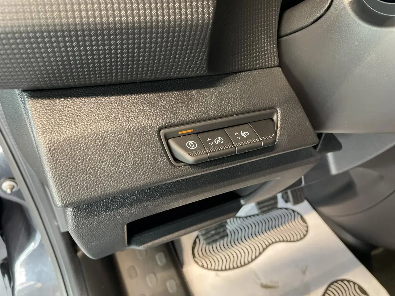 Gros plan sur les commandes sous le tableau de bord côté gauche du Renault Trafic Fourgon gris Comète 2025.