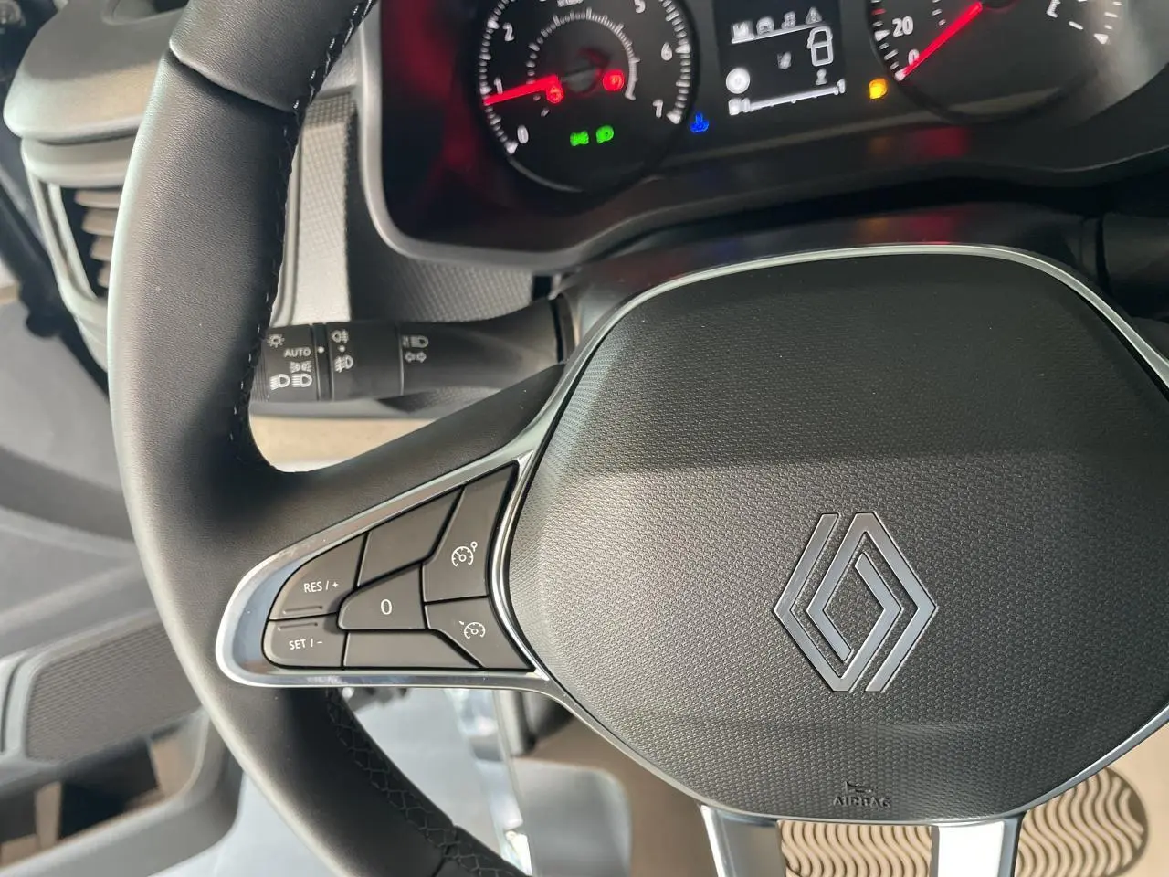 Gros plan sur le volant noir du Renault Trafic Fourgon 2025 avec commandes intégrées et tableau de bord partiellement visible.
