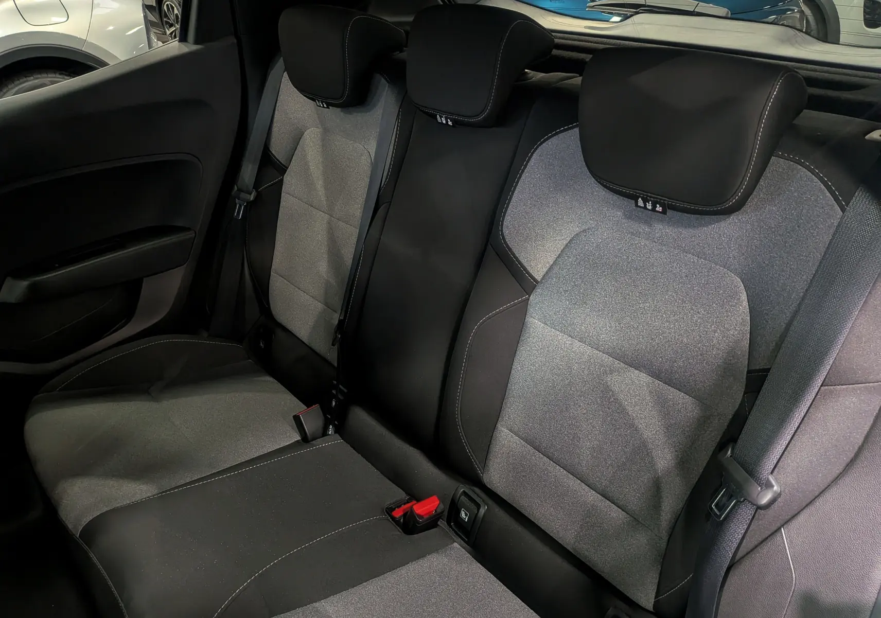 Vue intérieure des sièges arrière en tissu gris et noir de la Renault Clio V 2025, avec appuie-têtes et ceintures visibles.