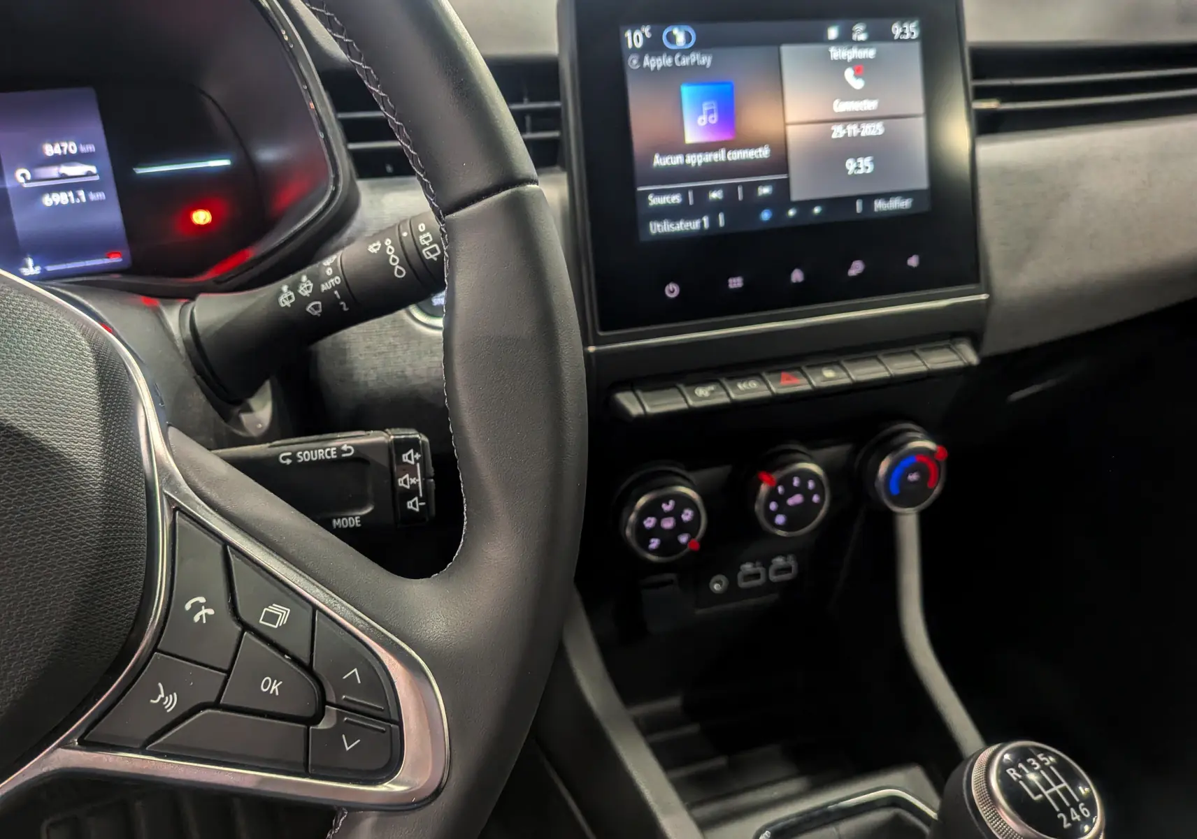 Vue intérieure de la Renault Clio V Blue dCi 100 en gris, montrant le volant, la boîte manuelle et l'écran tactile central.