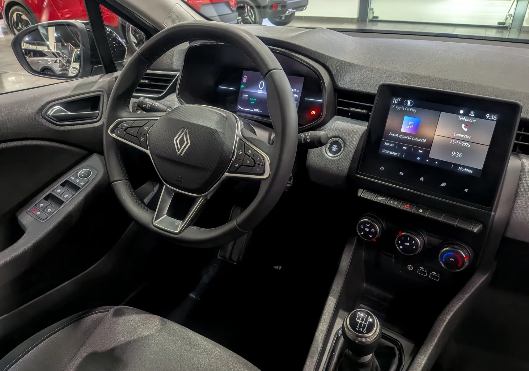 Vue intérieure côté conducteur de la Renault Clio V gris Rafale, avec volant multifonctions et écran tactile central.