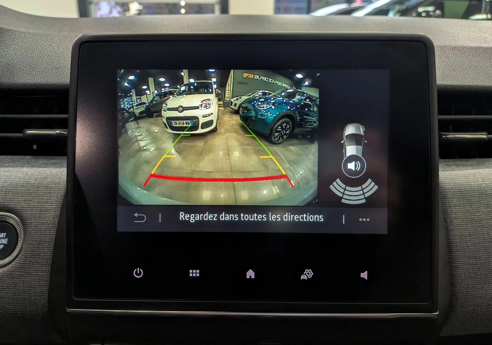 Écran central de la Renault Clio V gris Rafale montrant la caméra de recul avec vue arrière et aides au stationnement.