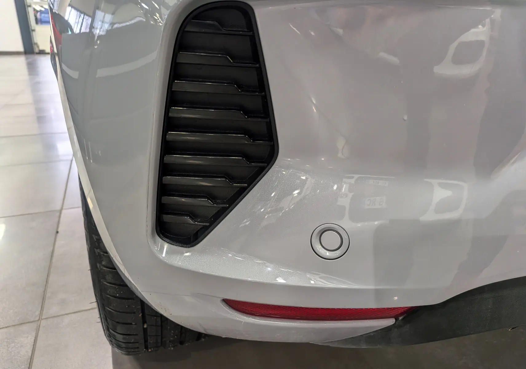 Gros plan sur l'aile arrière gauche gris Rafale d'une Renault Clio V avec capteur de recul et prise d'air noire.