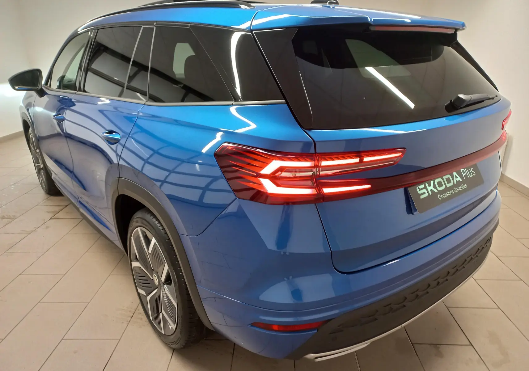 Vue 3/4 arrière droite du Skoda Kodiaq 2024 bleu RS avec feux LED allumés et jantes alliage 20 pouces anthracite.