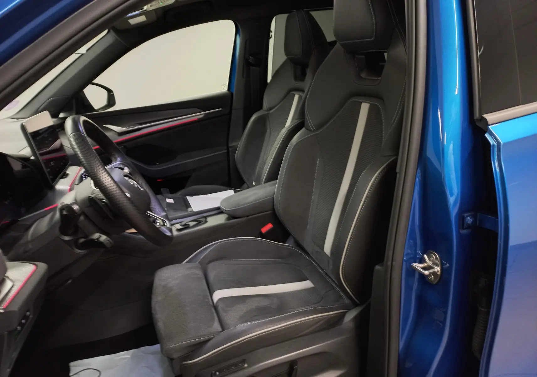 Écran tactile central du Skoda Kodiaq 2024 affichant les stations radio FM/DAB dans un intérieur avec surpiqûres blanches et bande rouge.