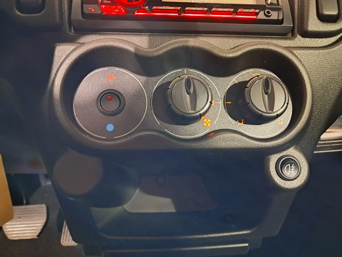 Gros plan sur les commandes de climatisation noires du tableau de bord de l’AIXAM MINAUTO E chic vert, côté conducteur.