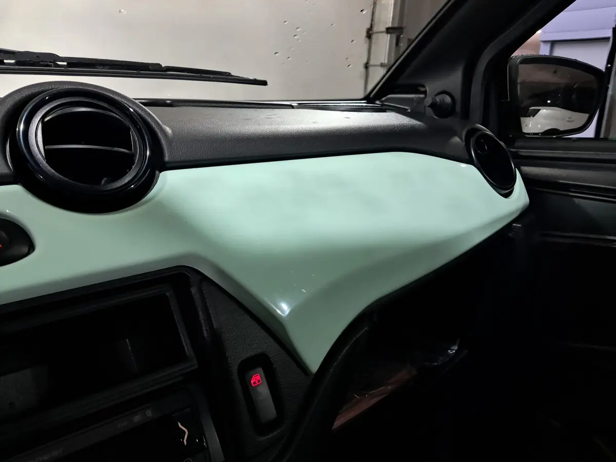 Vue intérieure côté passager du tableau de bord vert clair de l'AIXAM MINAUTO E chic 2026 avec aérateurs ronds noirs.