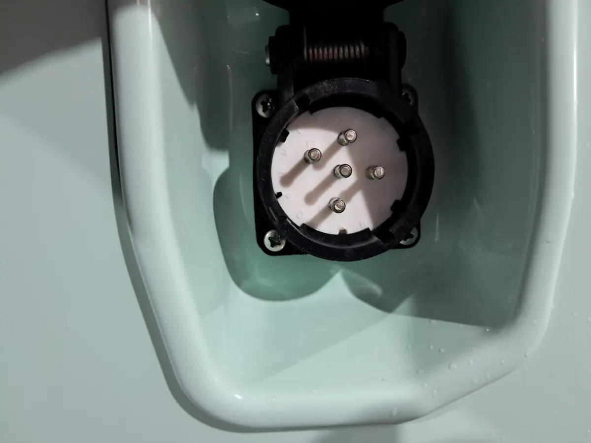 Gros plan sur la prise de recharge électrique intégrée dans la carrosserie verte de l'AIXAM MINAUTO E chic 2026.