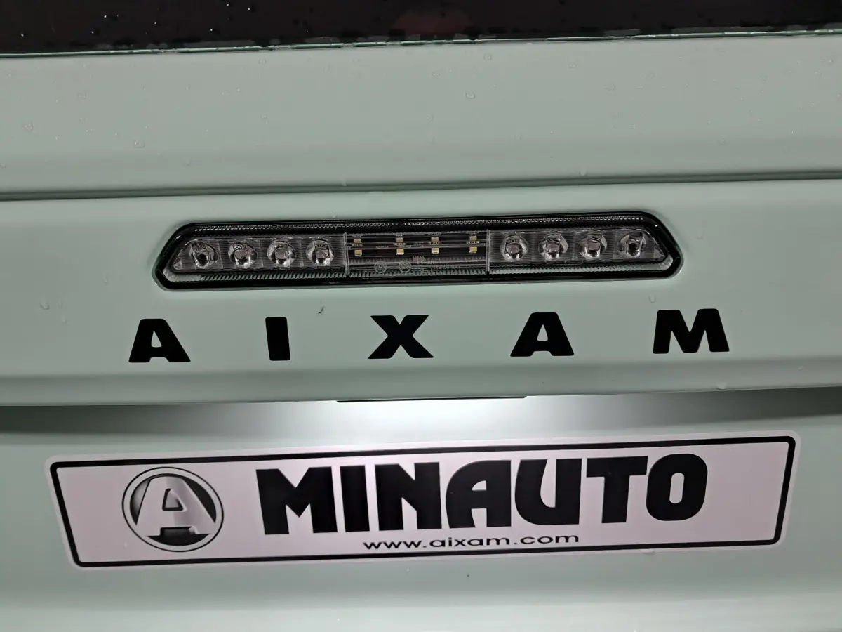Gros plan sur l’arrière vert clair de l’Aixam MINAUTO avec feu stop LED et logo distinctif visible.