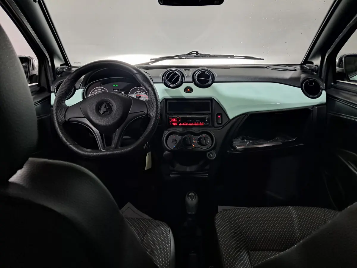Vue intérieure avant de l'AIXAM MINAUTO E chic 2026, tableau de bord vert et volant noir avec commandes visibles.