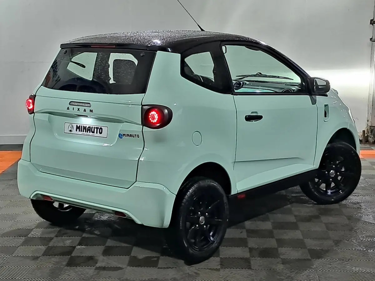 Vue 3/4 arrière droite de l'AIXAM MINAUTO E chic 2026 vert avec rétroviseur caméra côté conducteur et jantes noires.