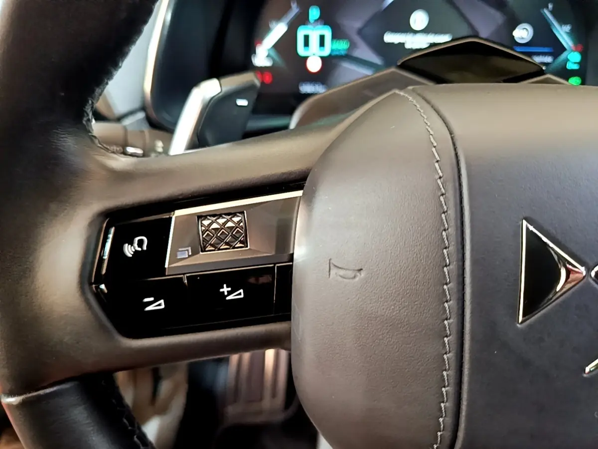 Gros plan sur le volant cuir noir du DS7 Crossback E-TENSE 4x4 300 avec commandes multifonctions et logo DS visible.