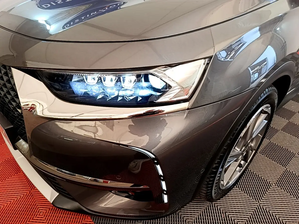 Gros plan sur l'avant droit gris foncé du DS7 Crossback E-TENSE 4x4 300 avec phares LED allumés et jante visible.