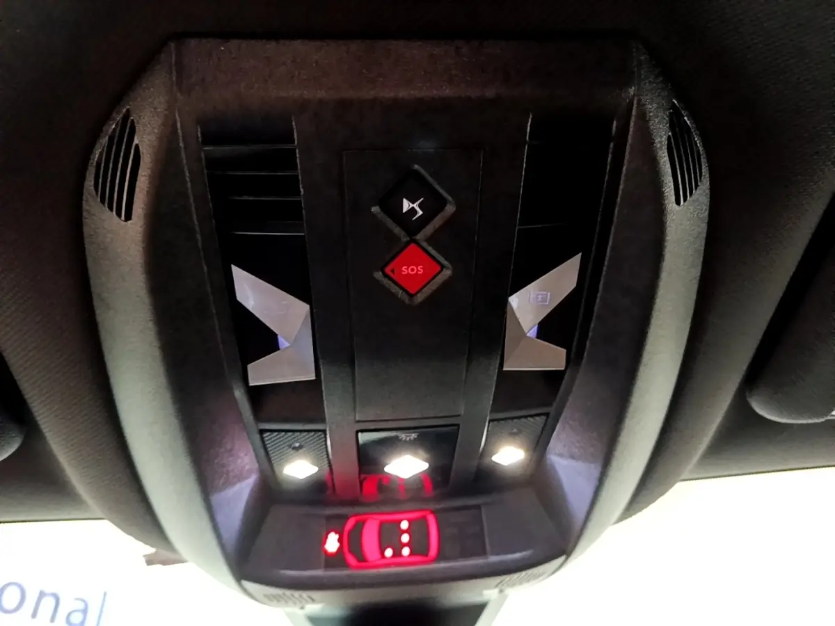 Vue en gros plan du panneau de commandes au plafond du DS7 Crossback gris foncé, avec bouton SOS rouge et éclairage LED blanc.