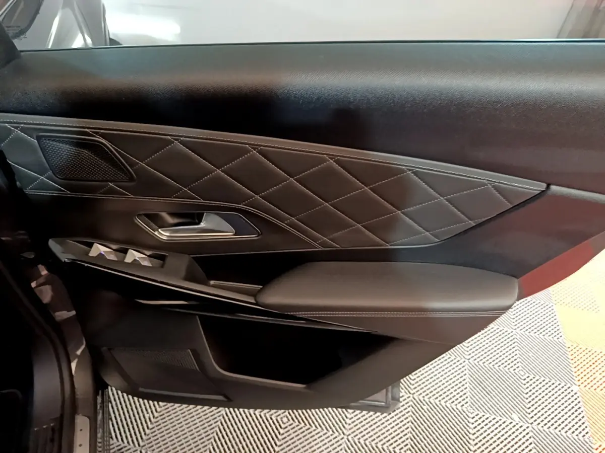 Gros plan sur la porte intérieure côté gauche du DS7 Crossback E-TENSE 4x4 300 RIVOLI avec cuir noir matelassé et commandes électriques.