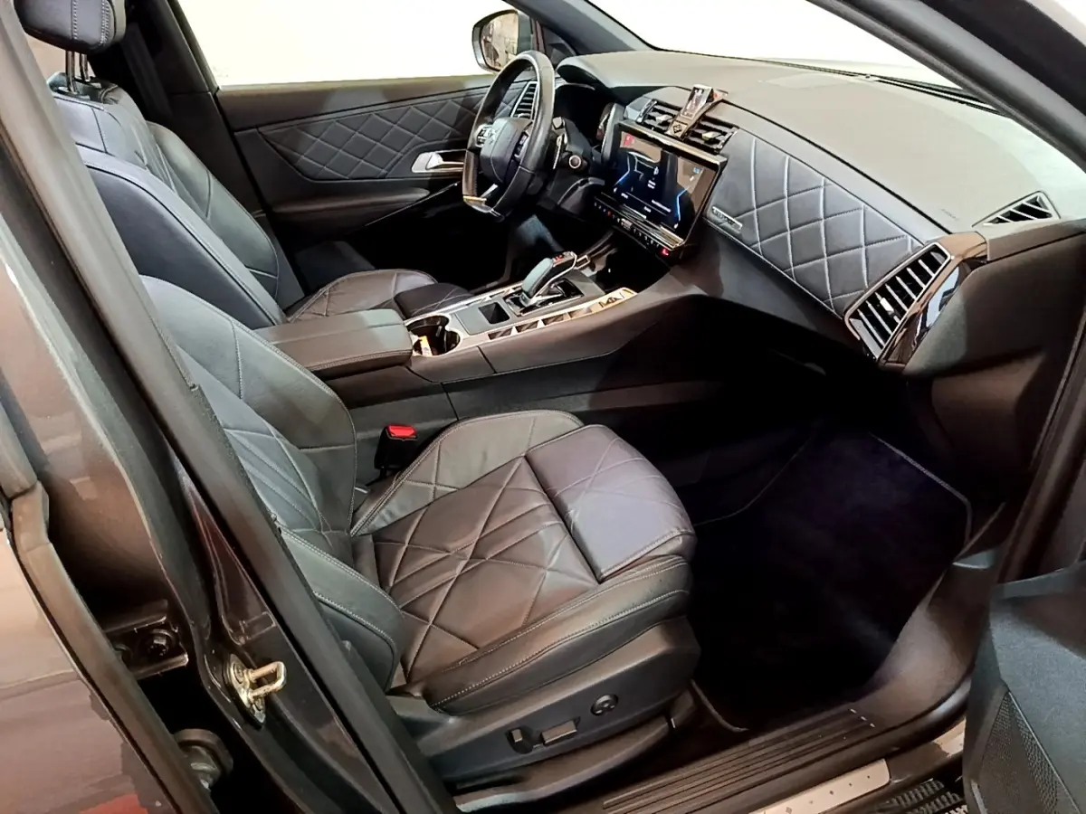 Vue intérieure côté conducteur du DS7 Crossback E-TENSE 4x4 300 RIVOLI 2021, cuir gris foncé matelassé et tableau de bord moderne.