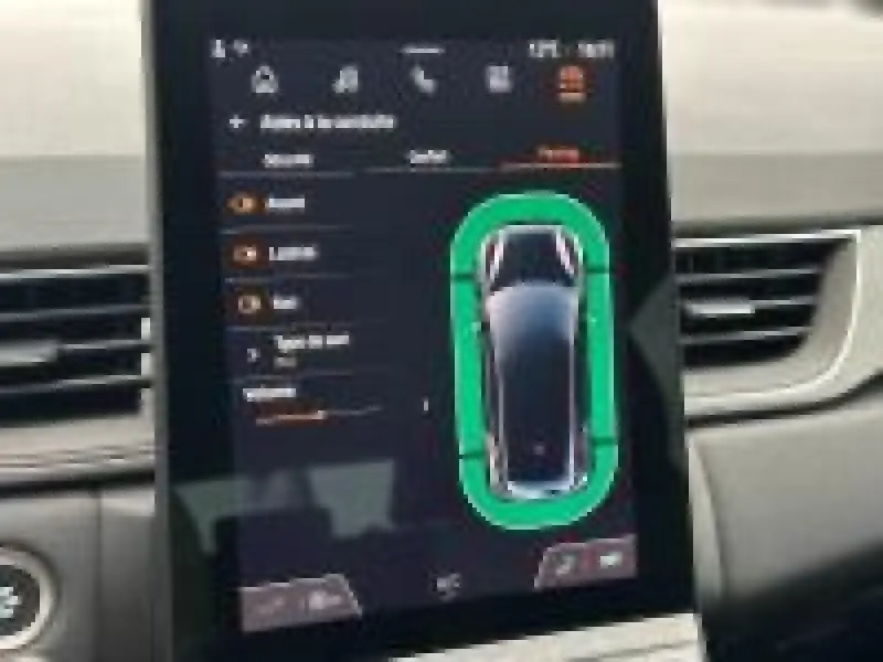 Écran tactile intérieur du Renault Captur 2025 montrant l'aide au stationnement avec vue du véhicule en plan dessus.