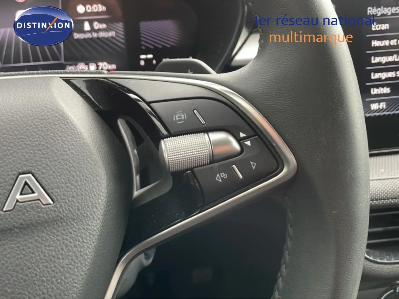 Gros plan sur le volant multifonction noir et gris d'une Skoda Fabia 2025, avec commandes intégrées et tableau de bord numérique en arrière-plan.