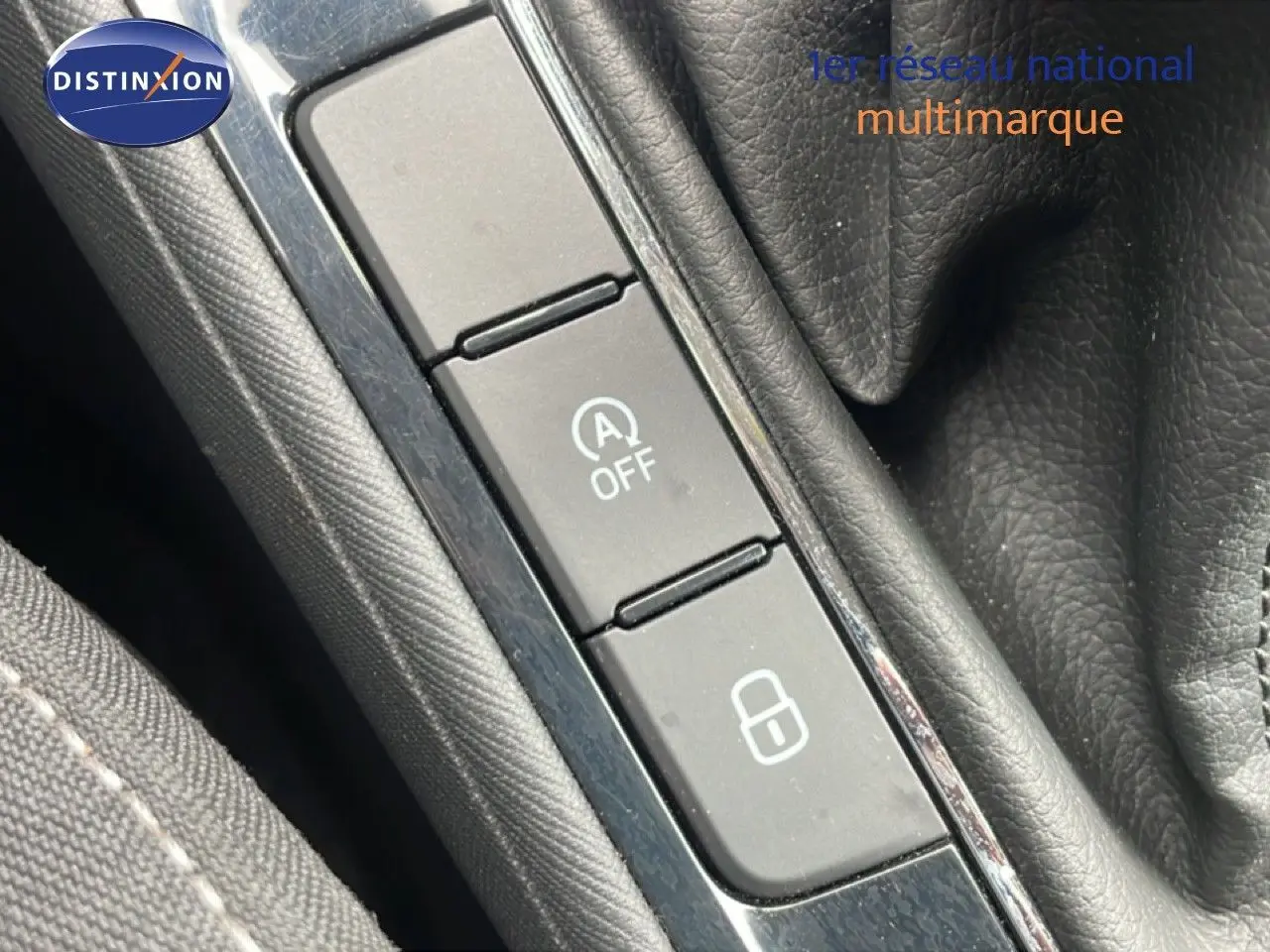 Gros plan sur les boutons de commande près du levier de vitesses dans une Skoda Fabia gris graphite, intérieur noir.