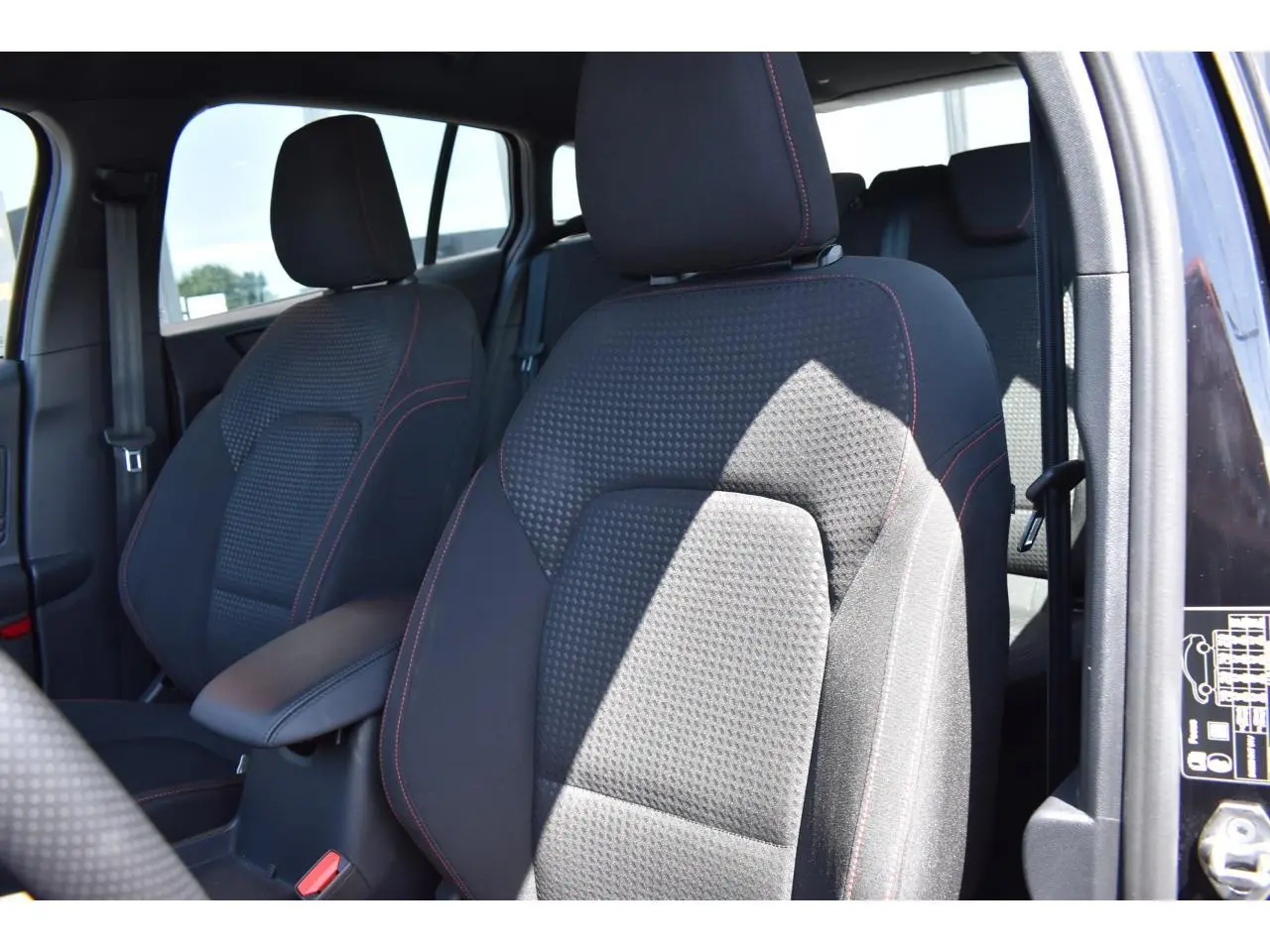 Gros plan sur les sièges avant noirs avec surpiqûres rouges de la Ford Focus SW 1.5 EcoBlue 115 Powershift ST LINE X.