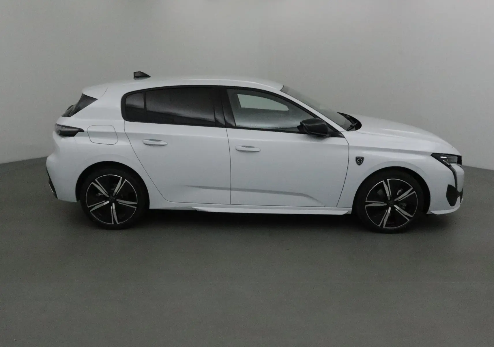 Profil côté gauche d'une Peugeot 308 blanche Okenite 2025 avec jantes noires et vitres teintées.