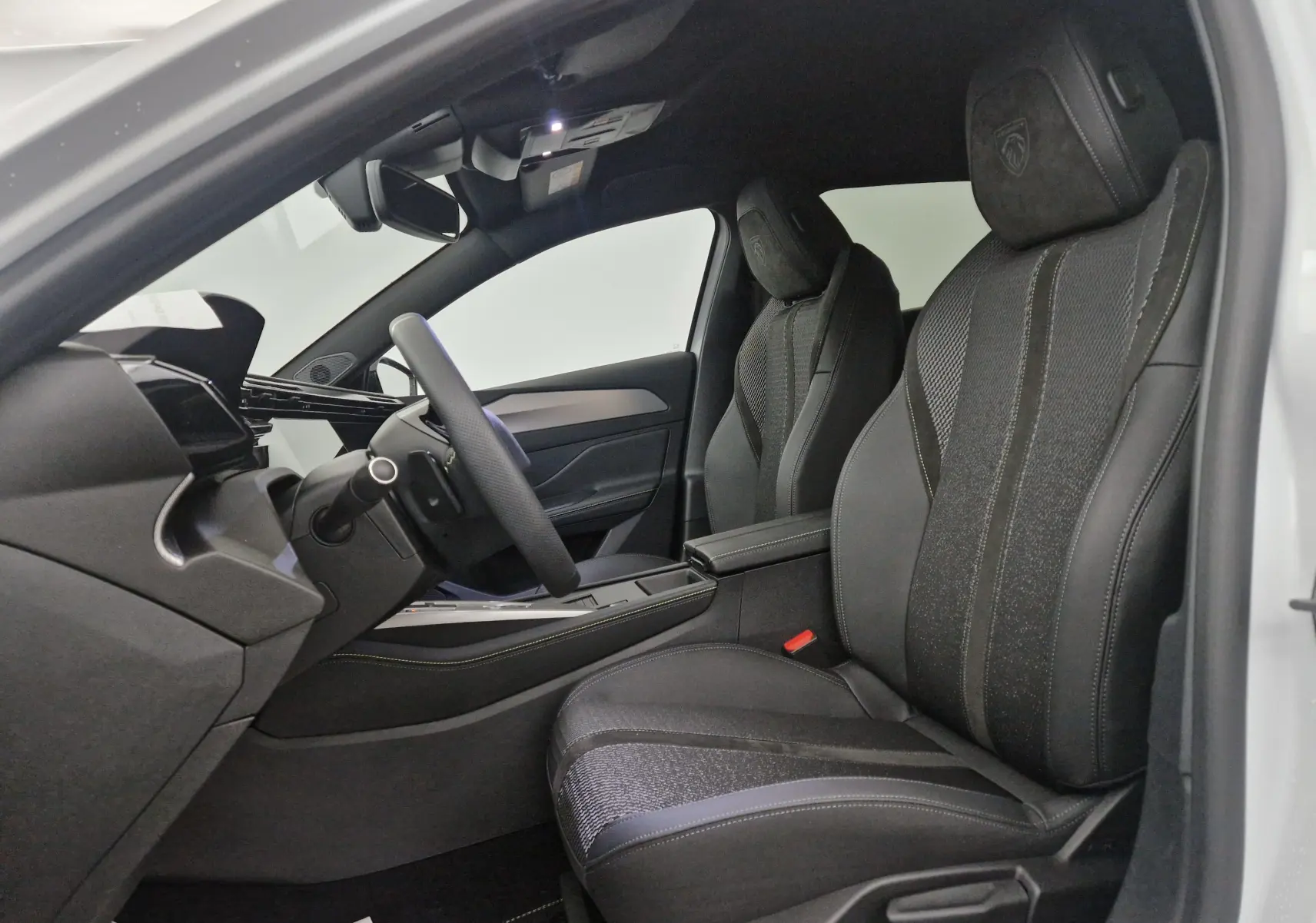Vue intérieure côté gauche du Peugeot 308 blanc Okenite 2025, sièges noirs avec logo GT brodé sur appuie-tête.