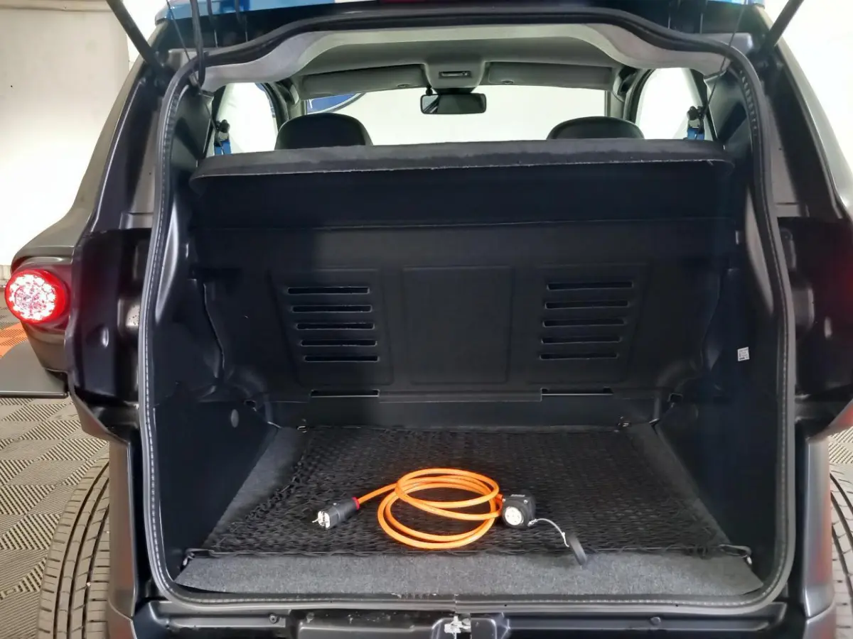 Vue arrière du coffre ouvert d’une Aixam Mega E-Scouty Evo bleu 2026 avec câble de recharge orange visible.