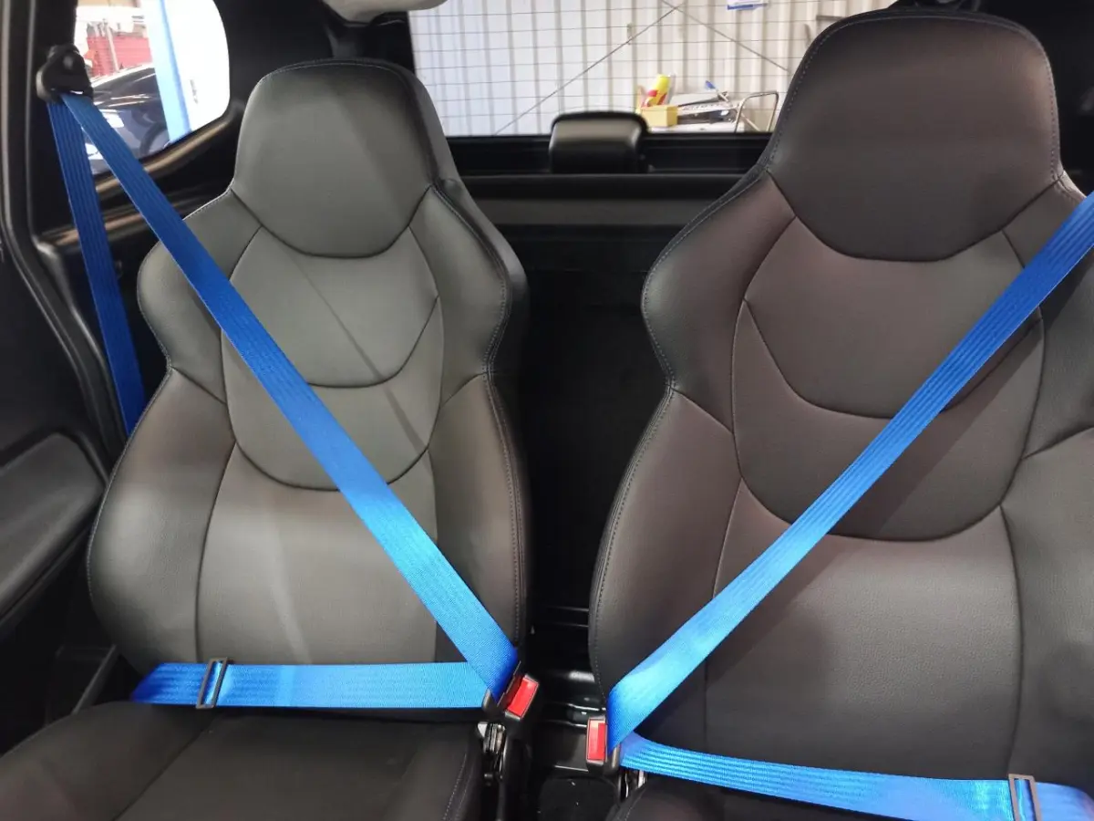 Vue intérieure rapprochée des sièges avant noirs avec ceintures de sécurité bleues dans l'AIXAM MEGA E-SCOUTY EVO 2026.