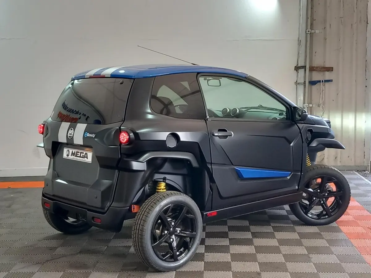 Vue 3/4 arrière droite de l'AIXAM MEGA E-SCOUTY EVO 2026 bleu mat avec bandes blanches et jantes noires.