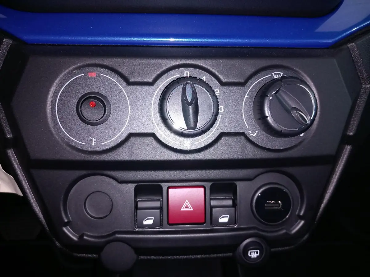 Gros plan sur la console centrale noire de l'AIXAM MEGA E-SCOUTY EVO bleu, montrant les commandes de climatisation et boutons.