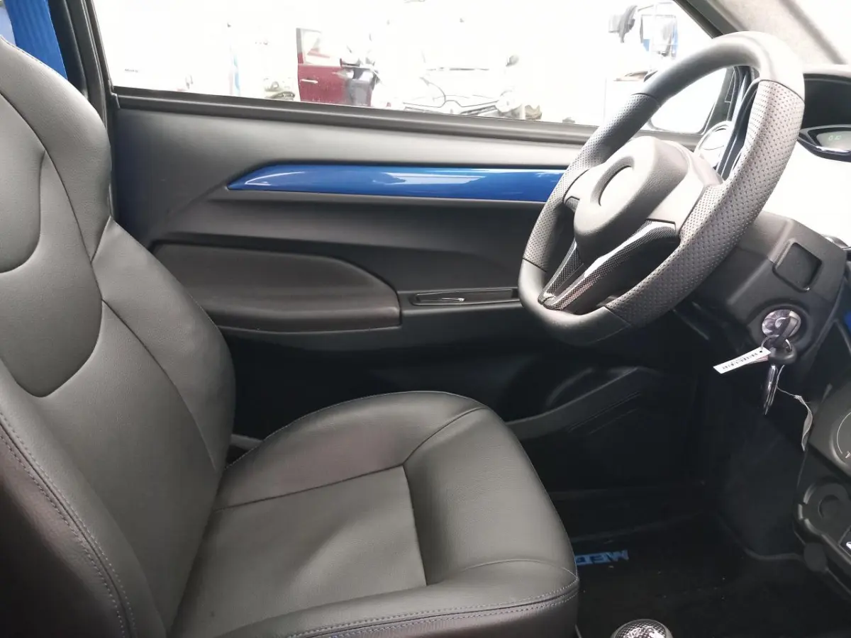 Vue intérieure côté conducteur de l'AIXAM MEGA E-SCOUTY EVO 2026 avec garniture bleue et sièges noirs en cuir.