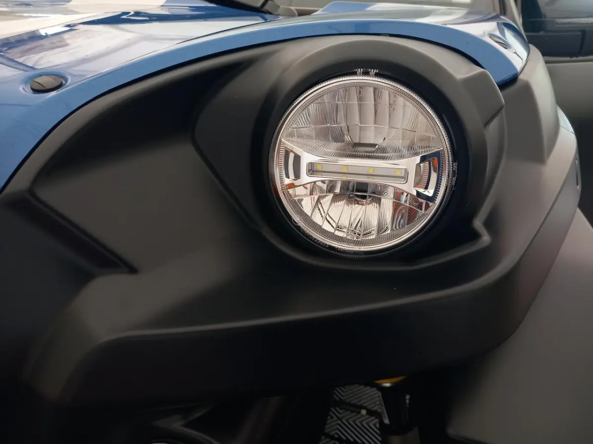 Gros plan sur le phare avant droit de l'AIXAM MEGA bleu électrique, soulignant son design moderne et robuste.