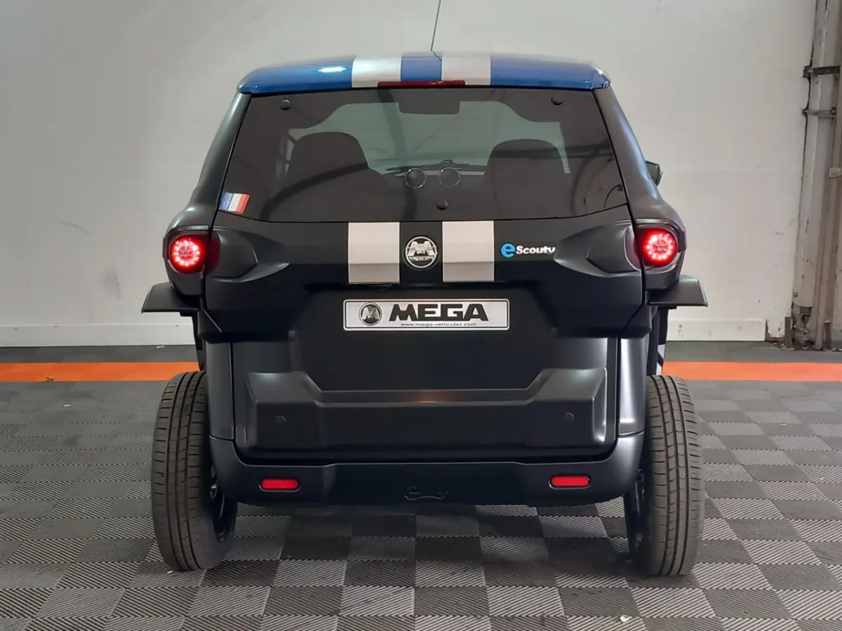 Vue arrière d’une Aixam MEGA E-Scouty Evo 2026 noire avec bandes blanches et feux arrière allumés en intérieur.