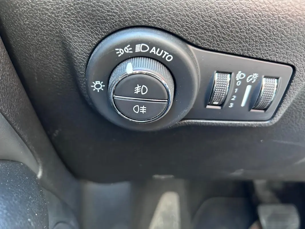 Gros plan sur le bouton de commande des phares avec réglages automatiques dans l'habitacle du Jeep Compass gris 2024.