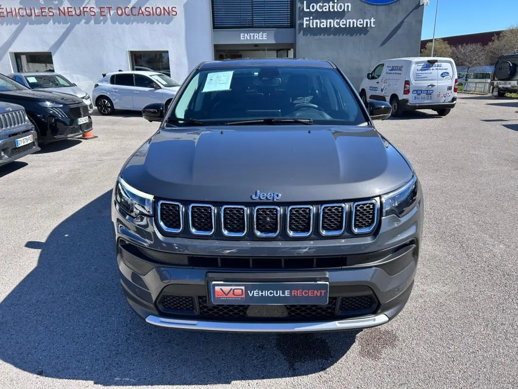 Vue avant d’un Jeep Compass gris 2024 avec calandre chromée et phares LED distinctifs, stationné en extérieur.