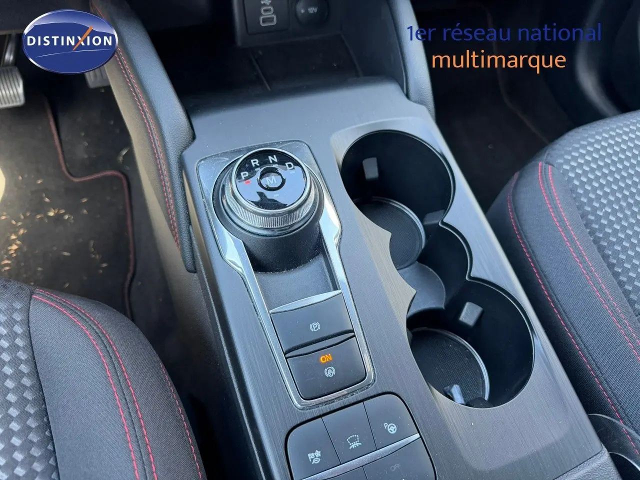 Vue rapprochée de la console centrale du Ford Kuga gris magnétique, avec sélecteur rotatif de boîte auto et porte-gobelets.