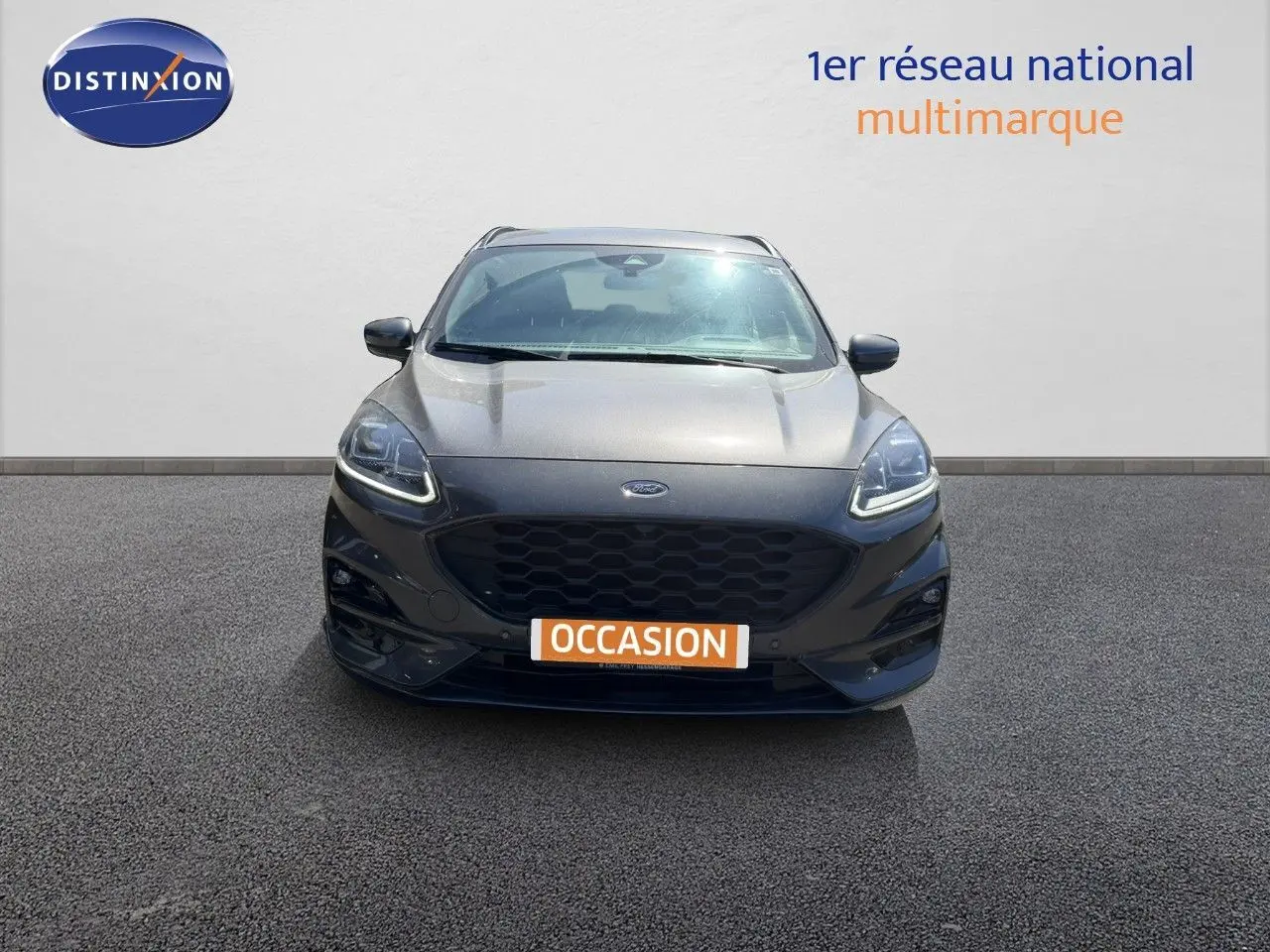Vue frontale d'un Ford Kuga 2024 gris magnétique métal avec calandre noire et feux LED allumés.