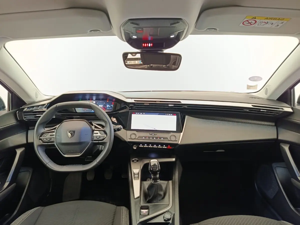 Vue intérieure avant de la Peugeot 308 PureTech 130 blanche, tableau de bord moderne avec écran tactile et volant cuir multifonctions.