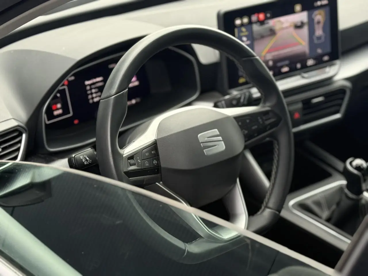 Vue intérieure rapprochée du volant en cuir et du tableau de bord numérique d'une SEAT LEON 1.5 TSI 115 Style 2025.