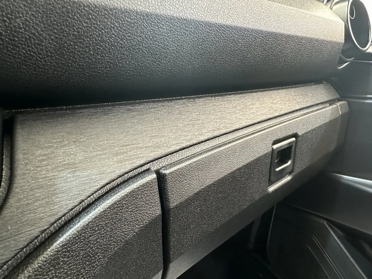 Gros plan sur la planche de bord noire texturée de l'AIXAM AMBITION 0.5 CITY PACK blanc, côté passager.