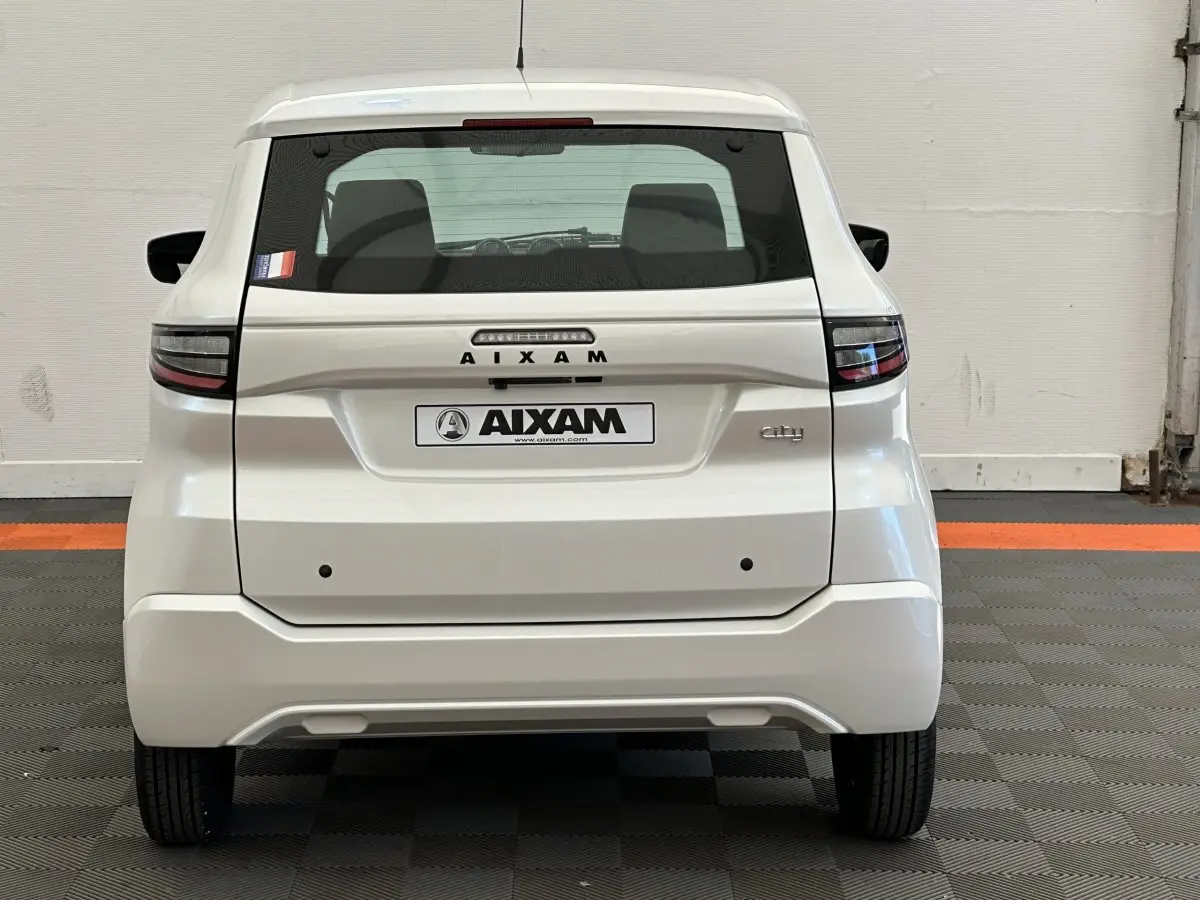 Vue arrière d'une Aixam Ambition 0.5 City Pack blanche, avec logo et feux arrière modernes visibles.