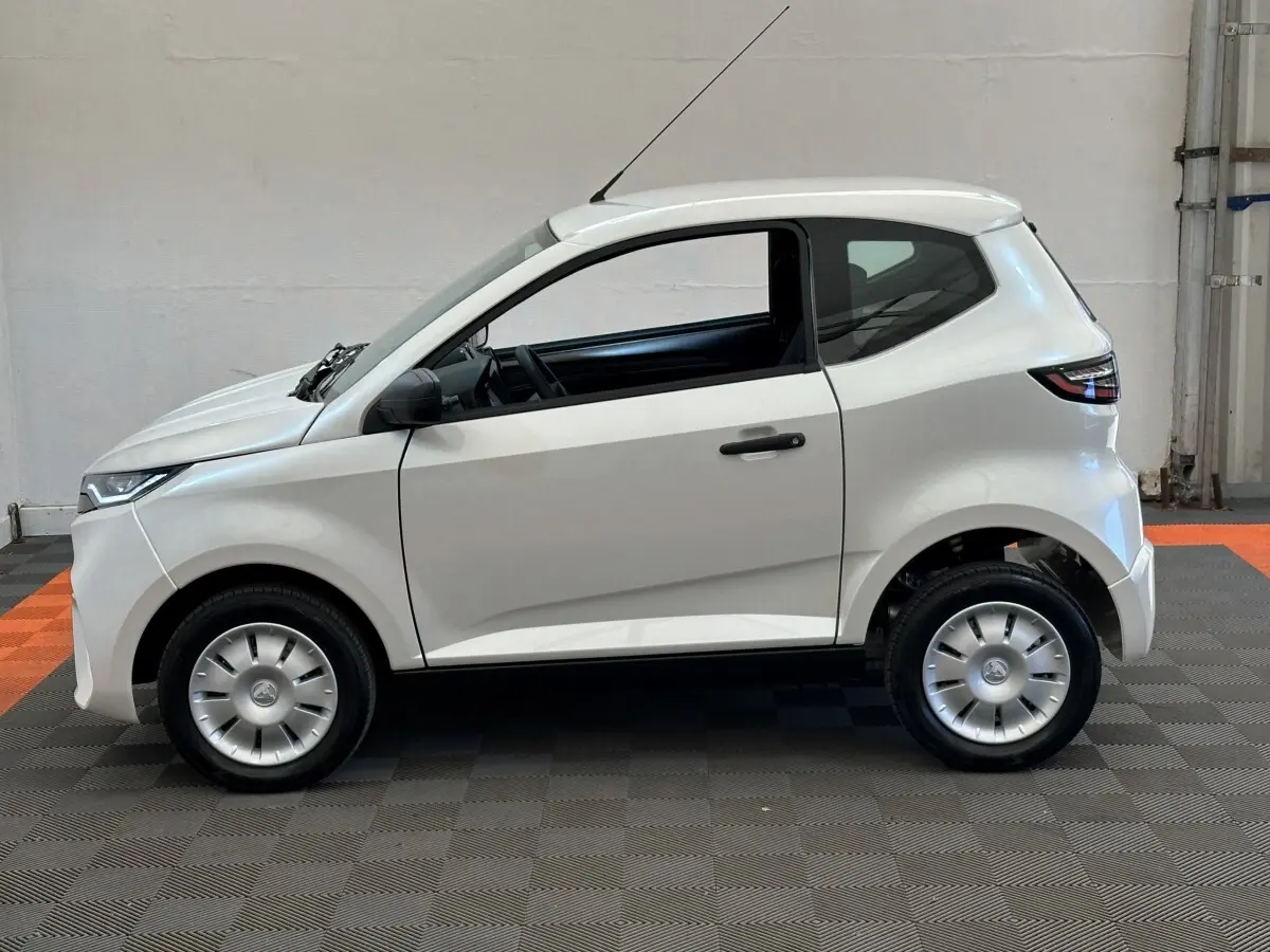 Vue de profil côté gauche de l'AIXAM AMBITION 0.5 CITY PACK blanche avec rétroviseur caméra côté conducteur.