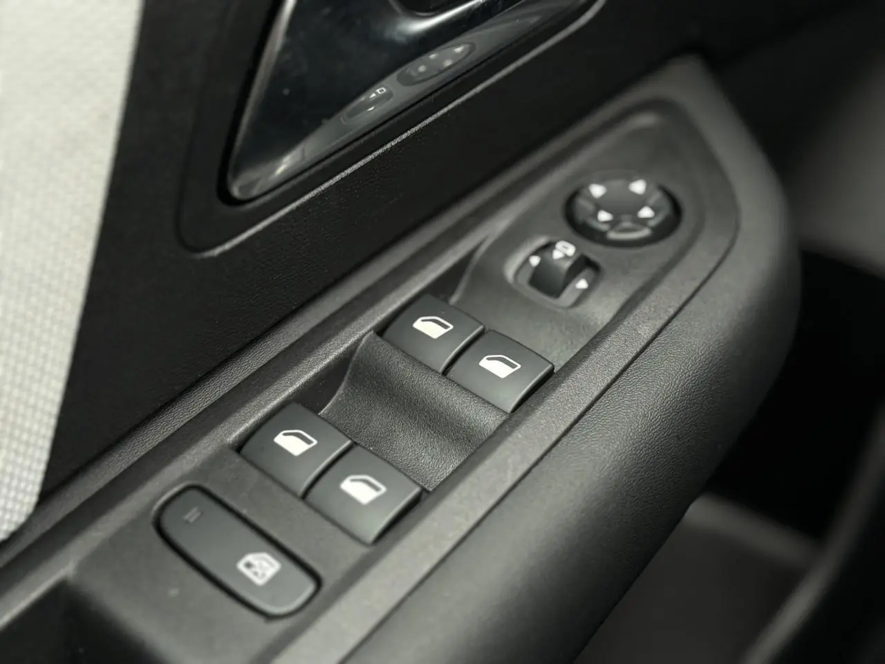 Gros plan sur les commandes de lève-vitres et rétroviseurs côté conducteur d'une Citroën C4 Hybrid 2025.